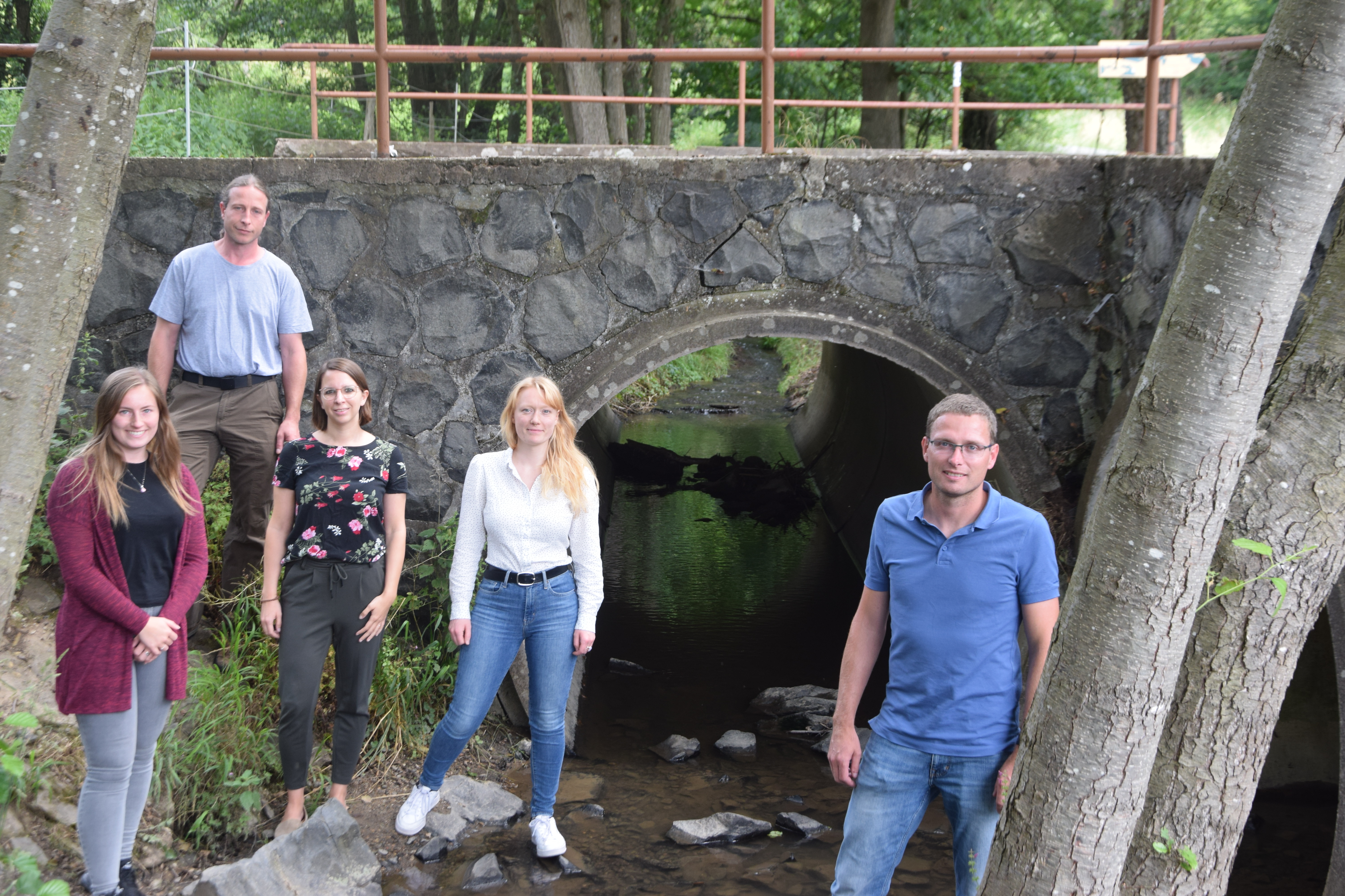 Fünf Teilnehmer stehen an einem Brückenbauwerk