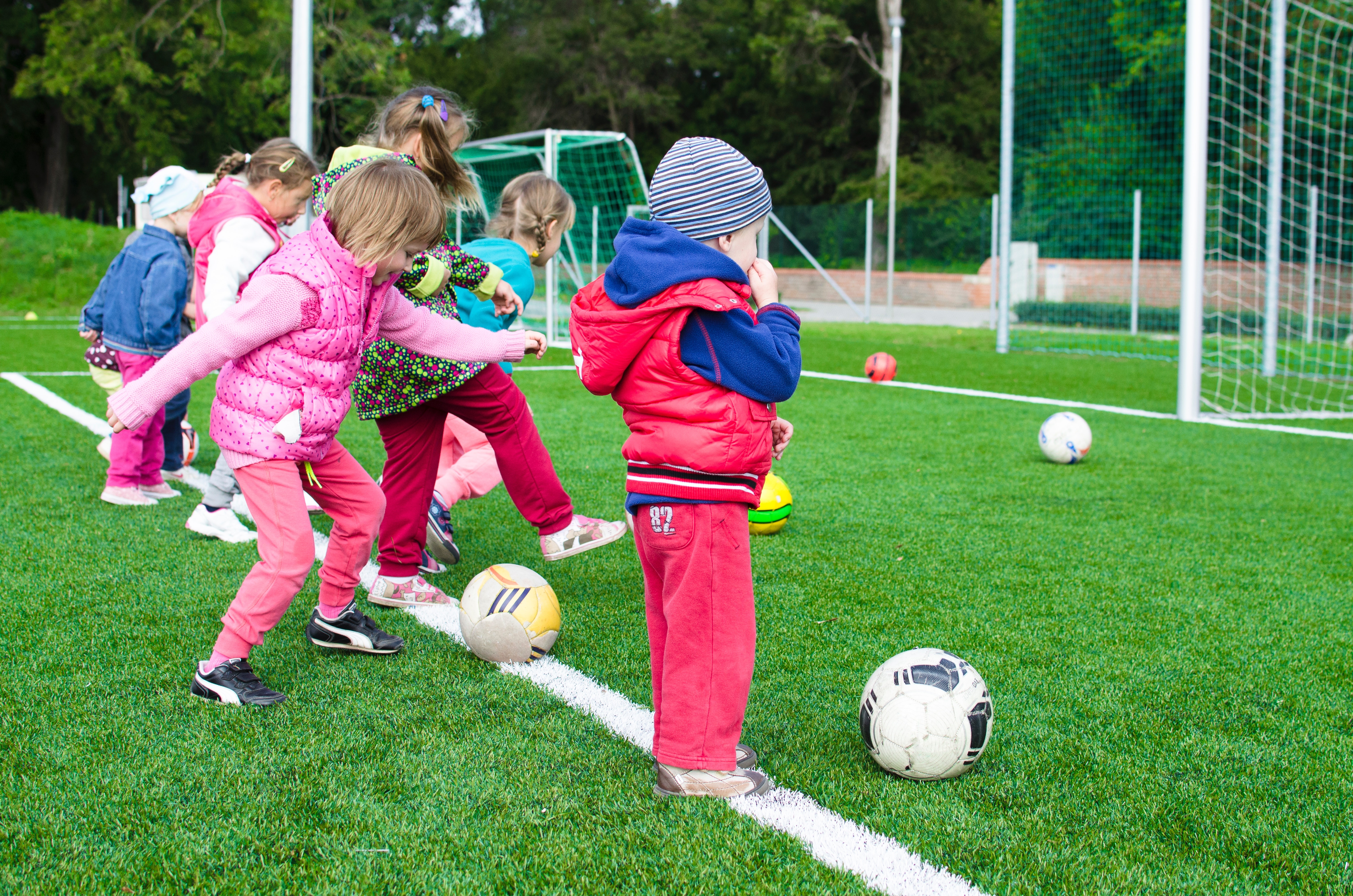 Kleinkinder spielen Fußball auf einem Rasenplatz