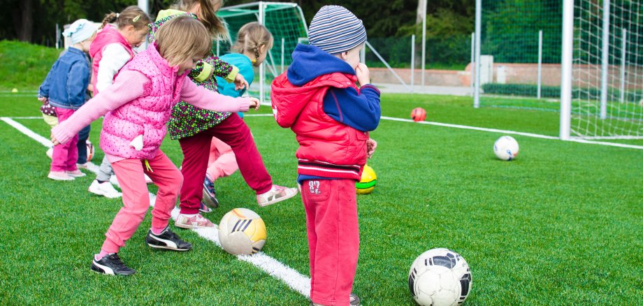 Kleinkinder spielen Fußball auf einem Rasenplatz